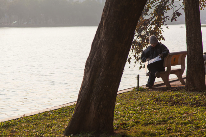 man on bench next to lake