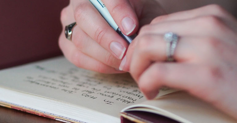 Close up of photographers hands writing in a book