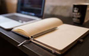 Pen and penciled business plan next to computer